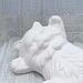Close up of unpainted ceramic kitty showing its face and front paws.